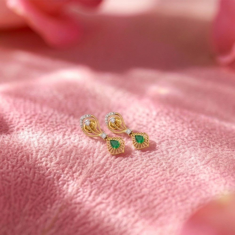 Gold and diamond drop earrings with gemstones on a pink surface