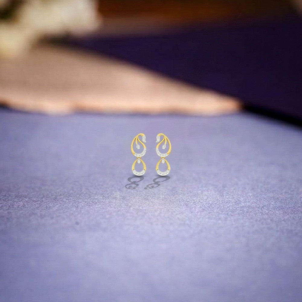 Gold and diamond drop earrings on a textured purple surface.