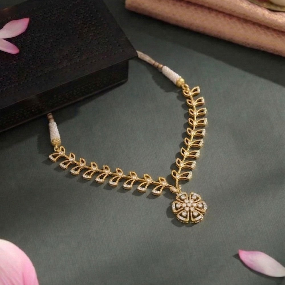 Gold necklace with floral design on a dark surface