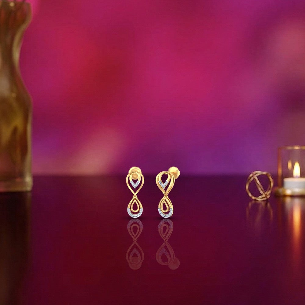 Gold and diamond drop earrings on a reflective surface.