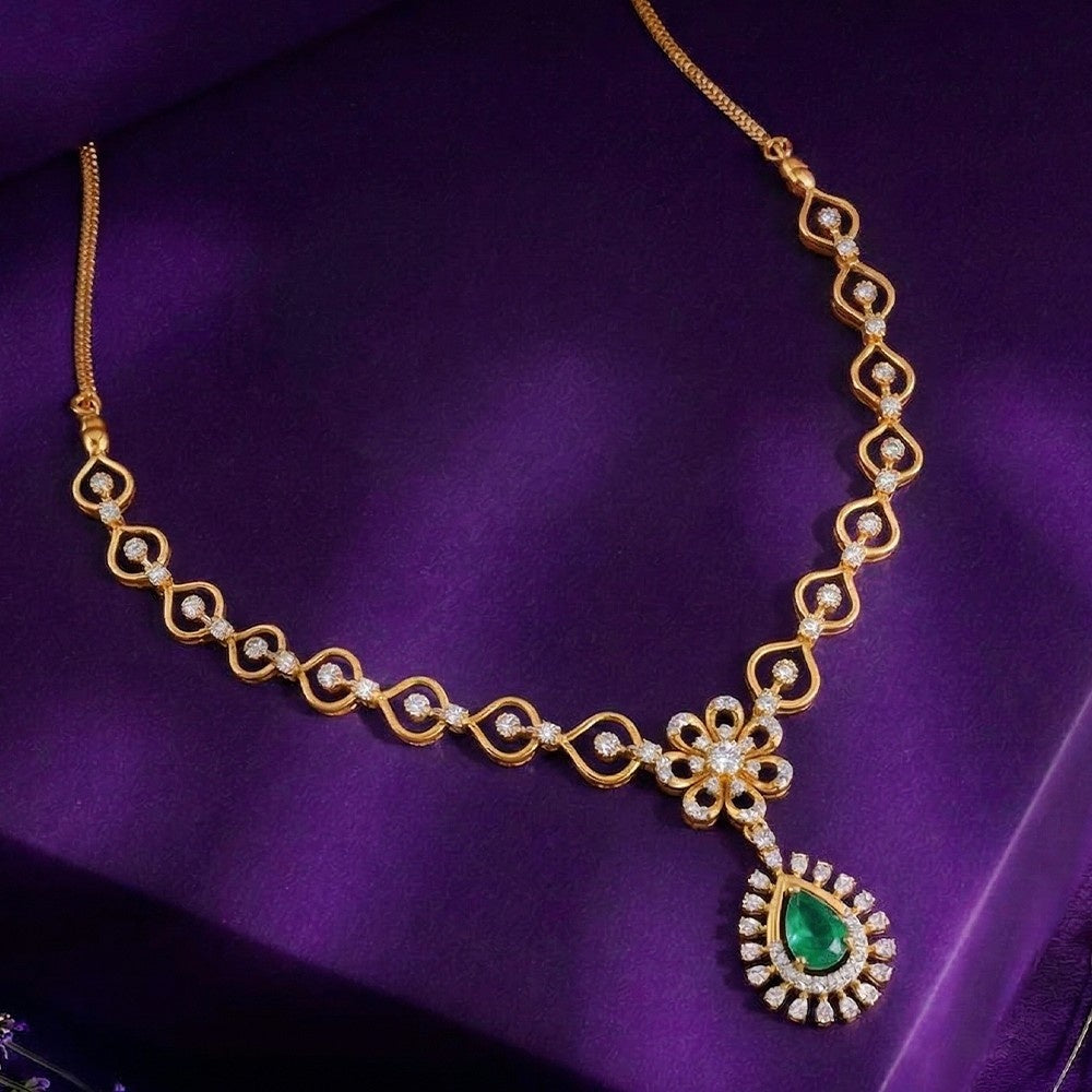 Gold necklace with green gemstone on a purple fabric background