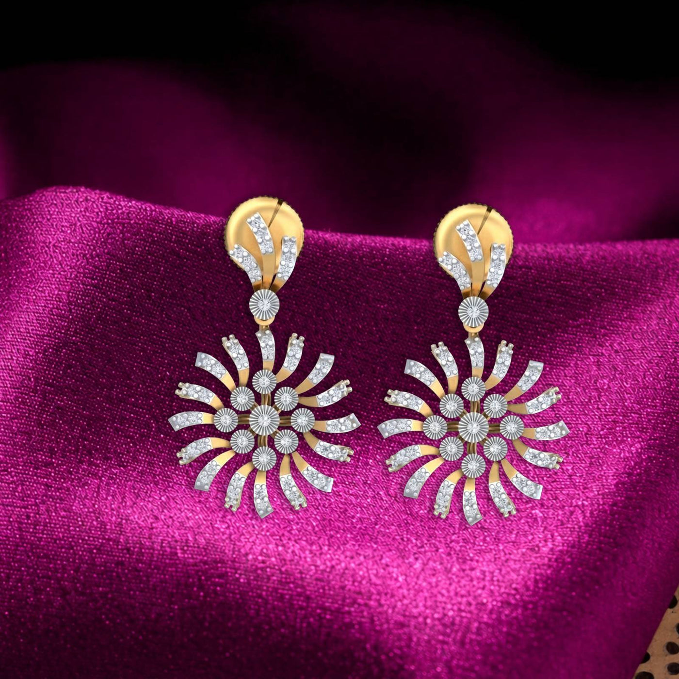 A pair of gold and diamond dangler earrings, displayed on a draped magenta satin fabric background.