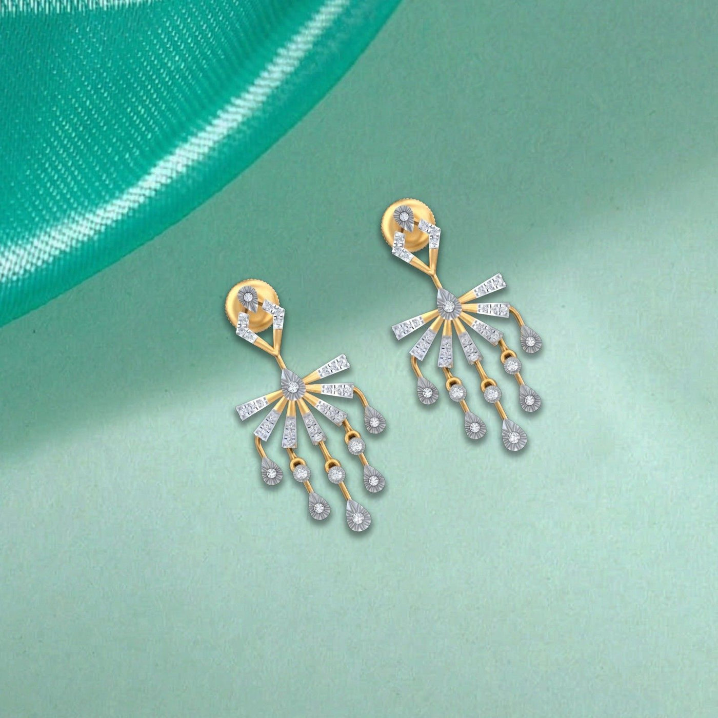 A pair of gold and diamond drop earrings, displayed on a light mint green background.