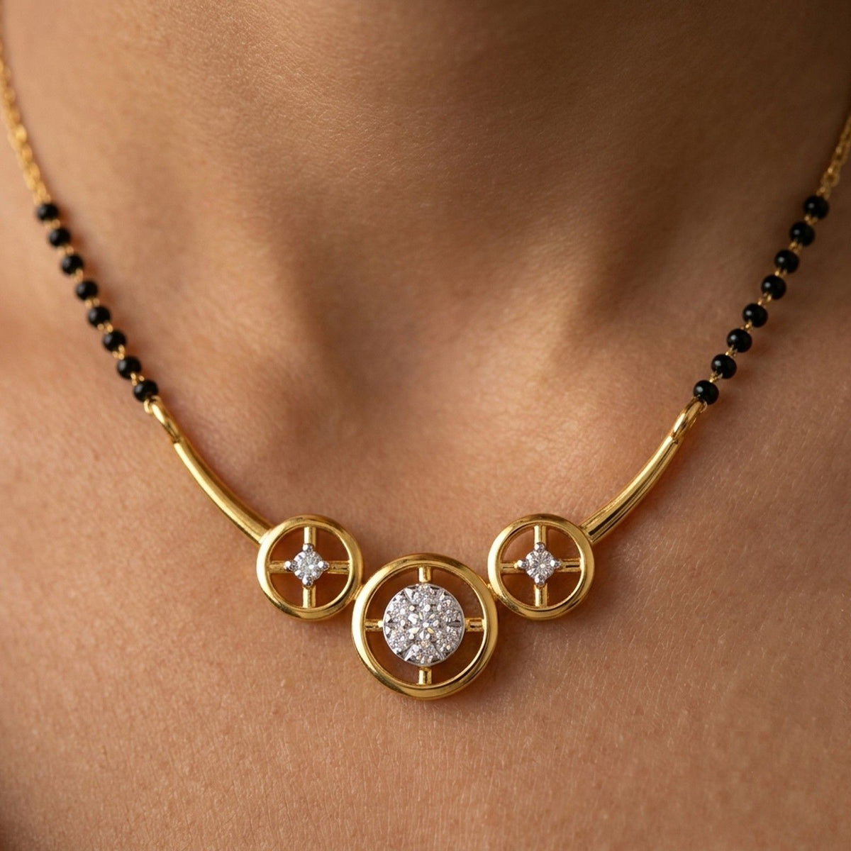 A close-up of a person wearing a gold chain mangalsutra with black beads featuring three diamond-accented open circles