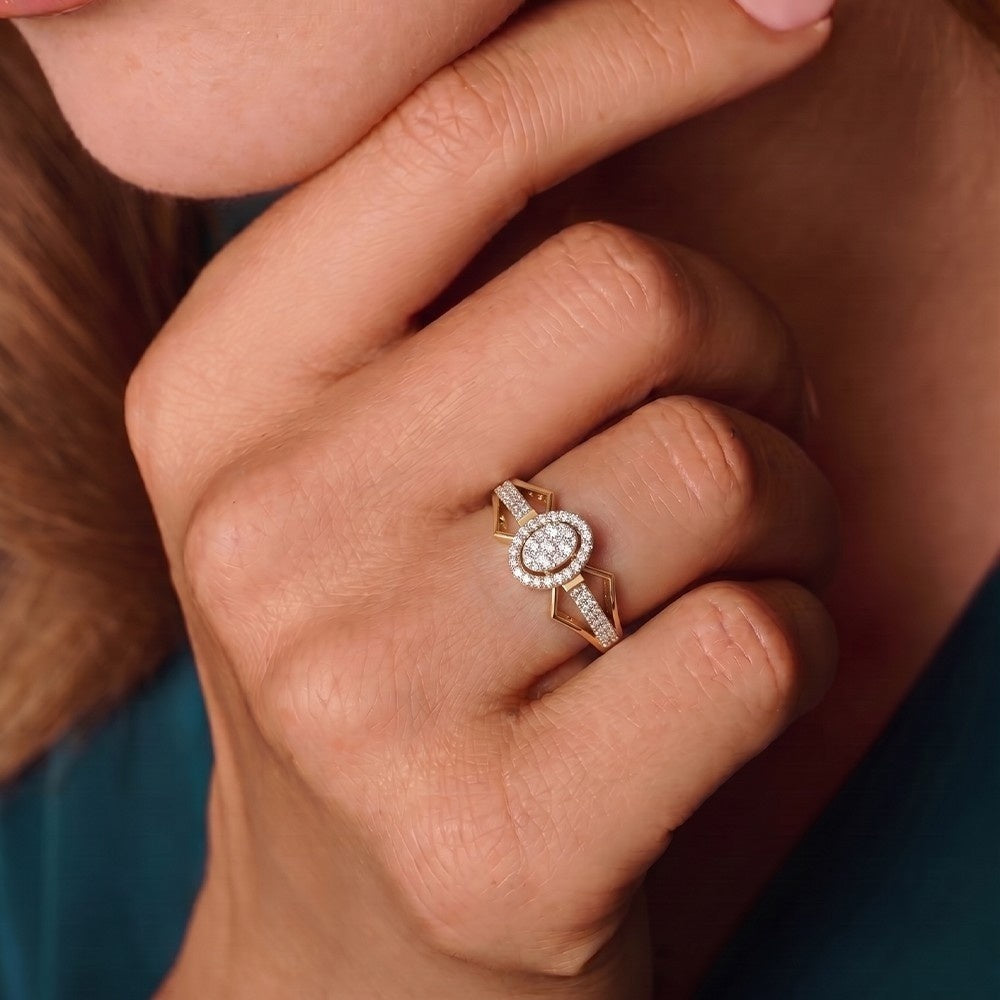 Close-up of a hand wearing a gold ring with a diamond on a blurred background.
