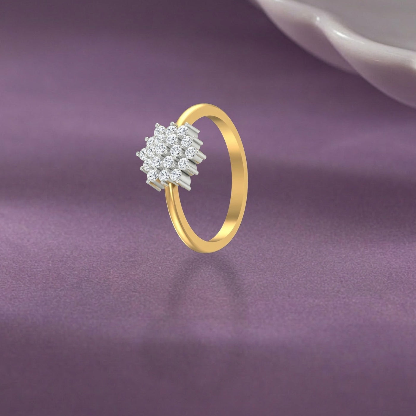 Gold ring with diamond cluster on a purple fabric background.