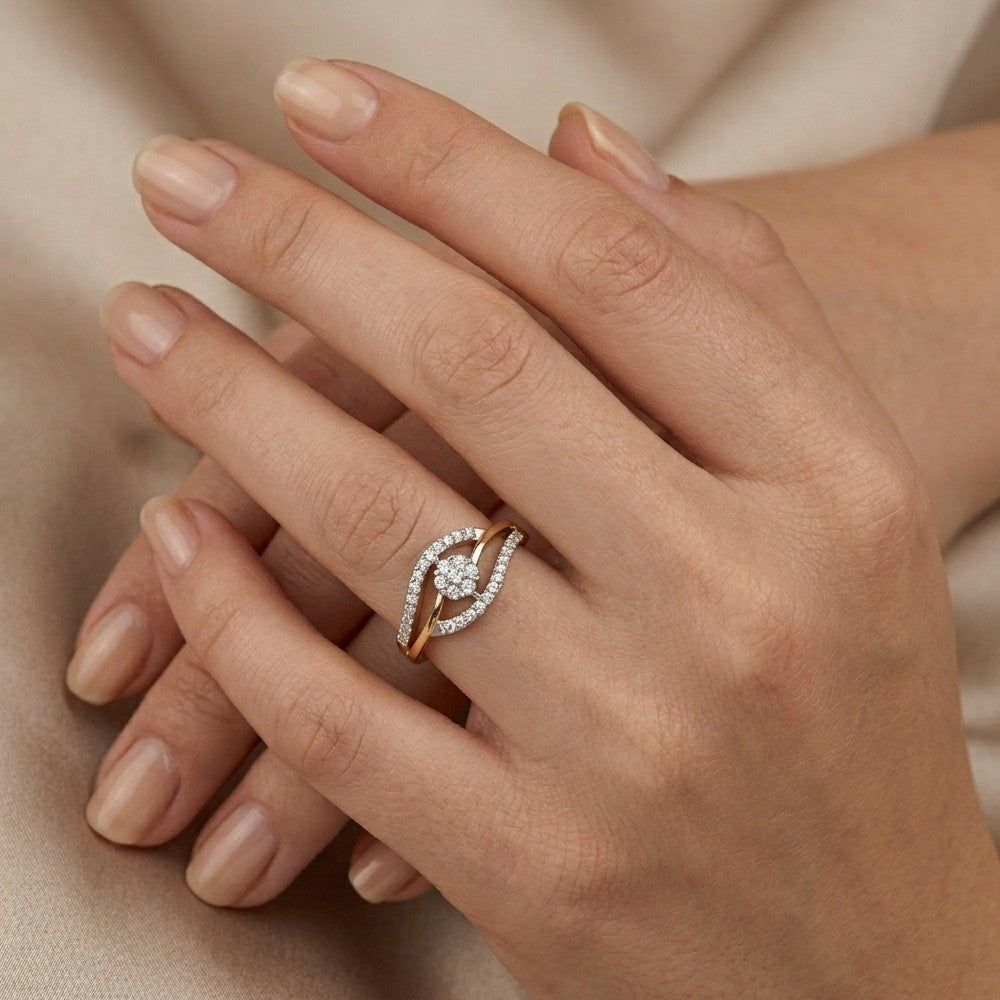 A close-up of a person's hands wearing a gold ring with a pavé diamond crescent design, set against a soft beige fabric background.