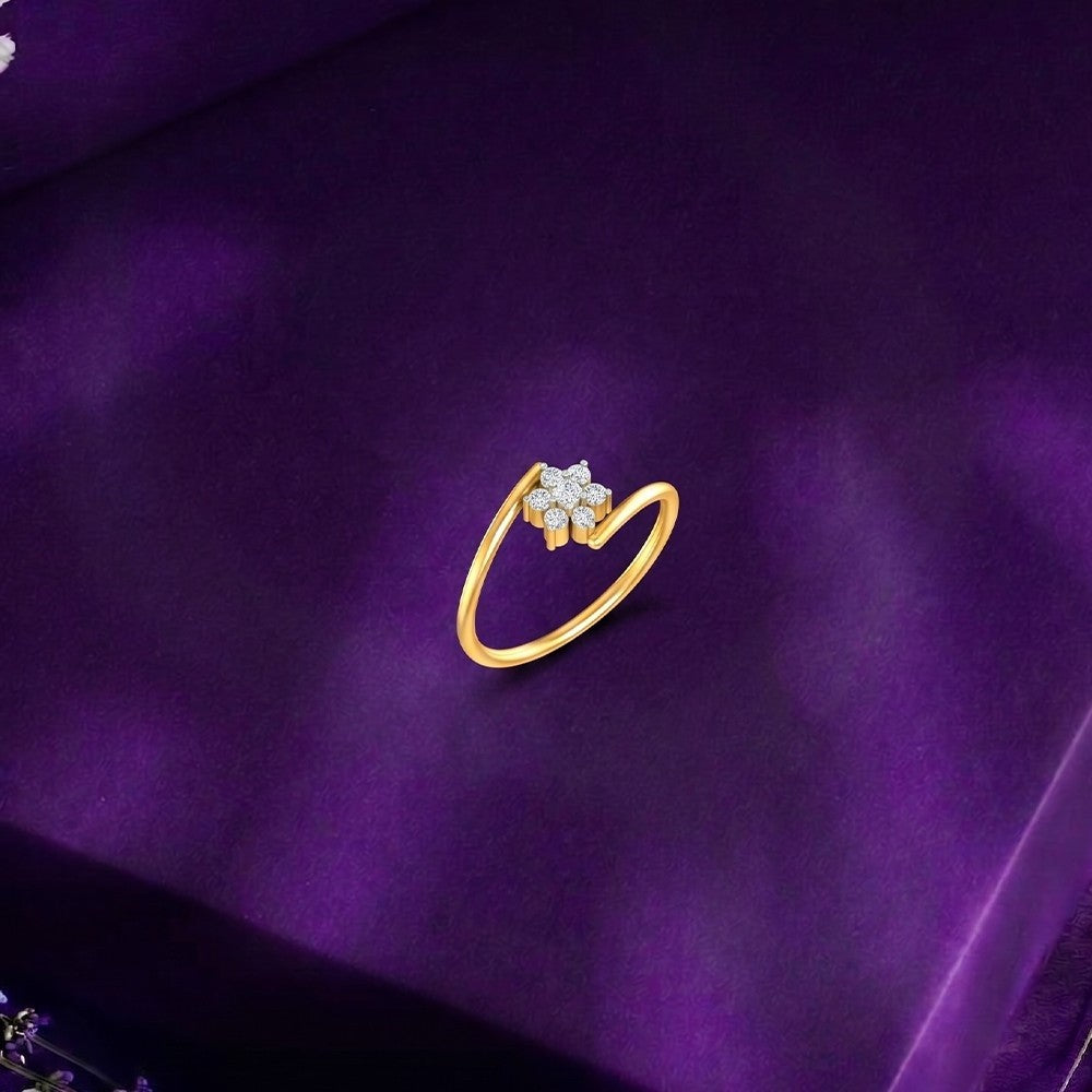 Gold ring with diamond floral design on a fabric surface. 