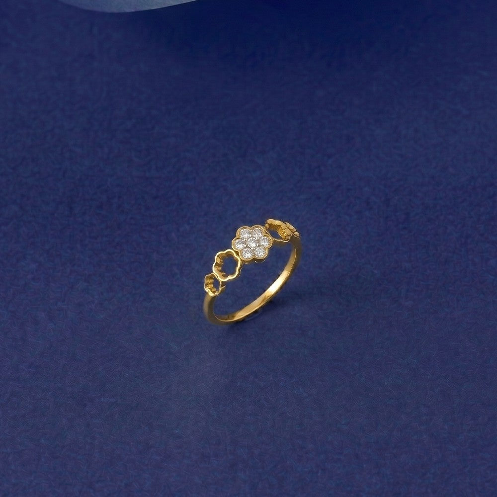 A gold ring featuring three small flower motifs, with the center flower detailed, set against a dark blue textured background.