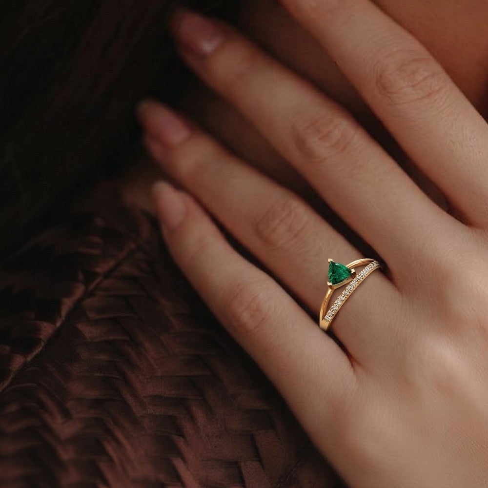 Gold ring with a green gemstone on a hand against a dark background