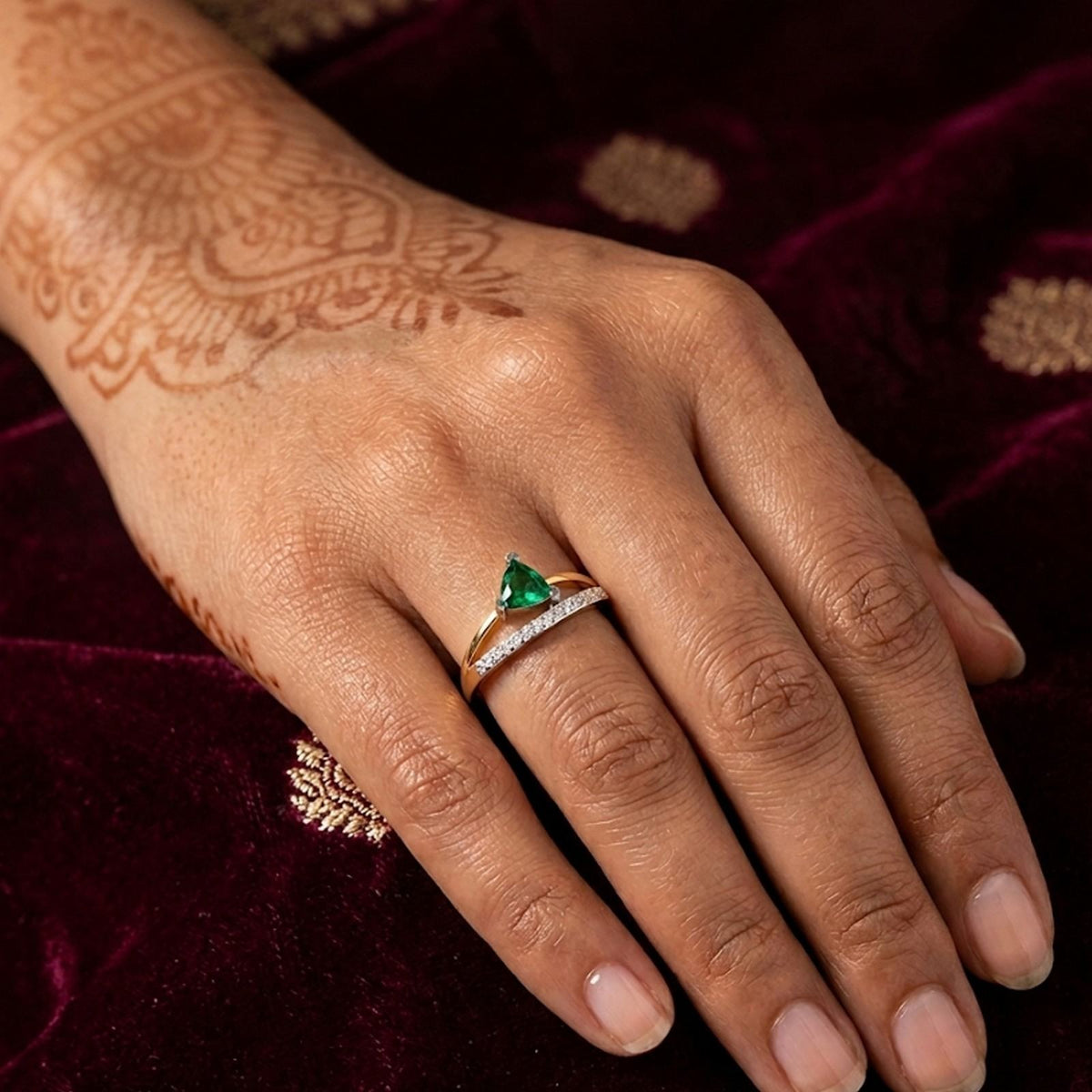 Gold ring with a green gemstone on a hand against a dark background