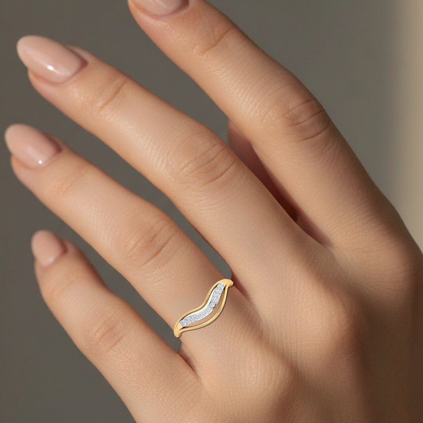 Gold ring with diamonds on a hand against a neutral background