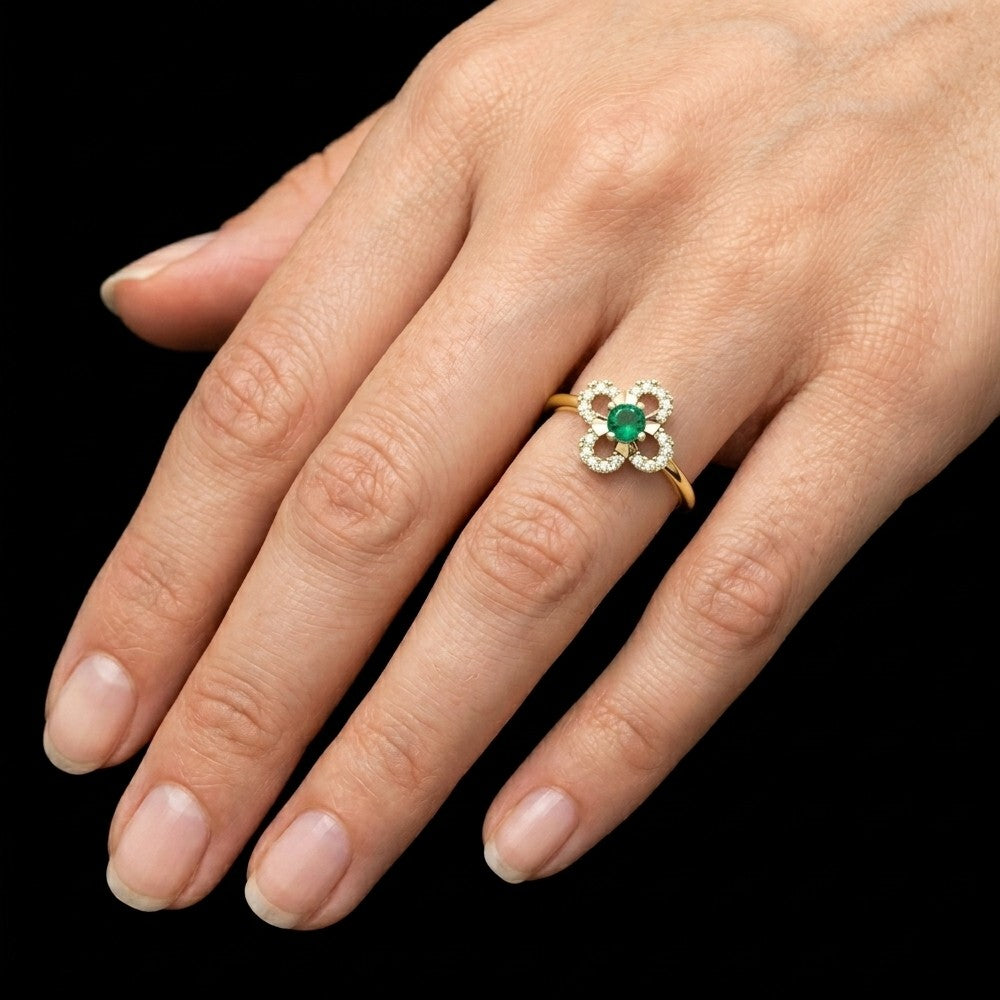 Close-up shot of a gold and diamond with floral-design and center emerald gemstone setting ring.