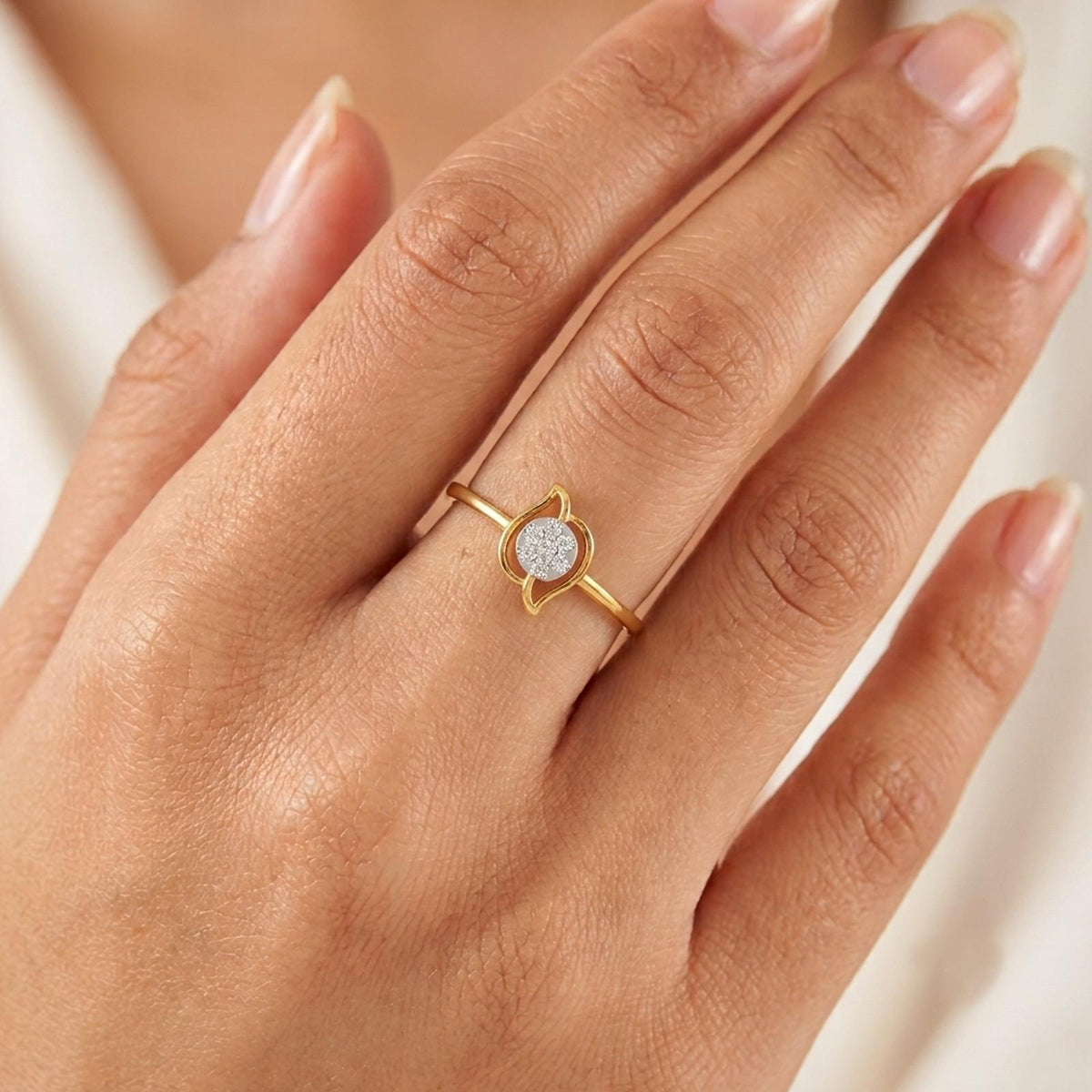 Gold and diamond with round-shaped cluster setting on a person's finger.