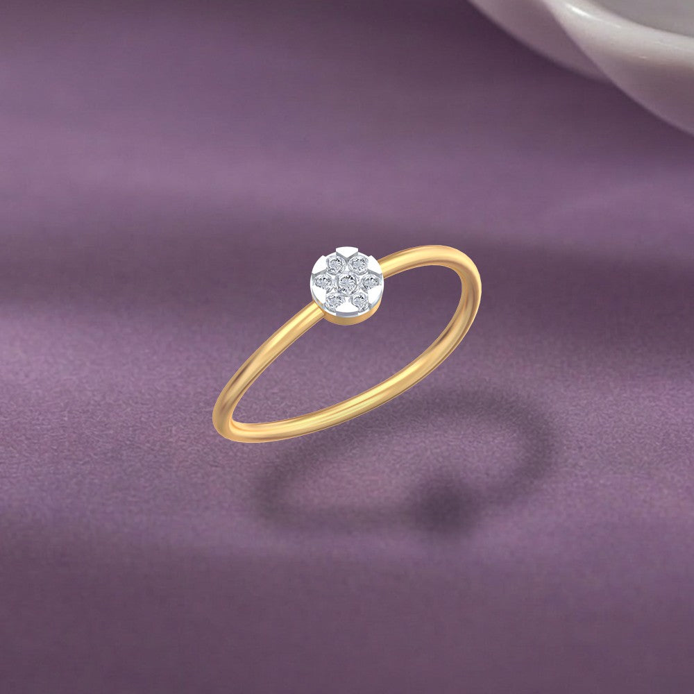 A delicate gold and diamond ring with a floral cluster setting, displayed on a textured purple surface.