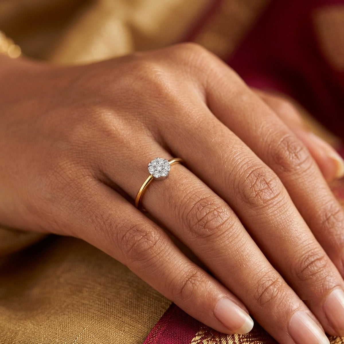 A delicate gold and diamond ring with a floral cluster setting, displayed on a person's finger.