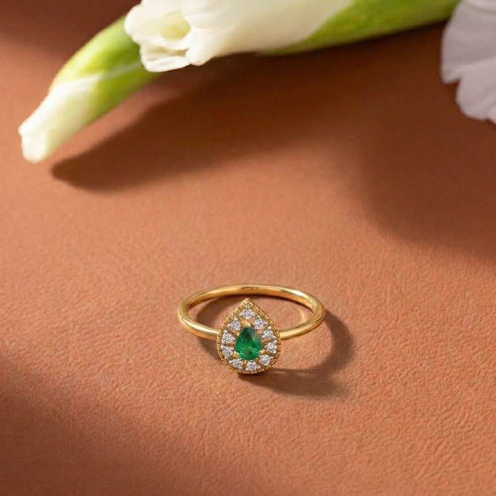 Gold and diamond with teardrop emerald gemsotne setting ring.