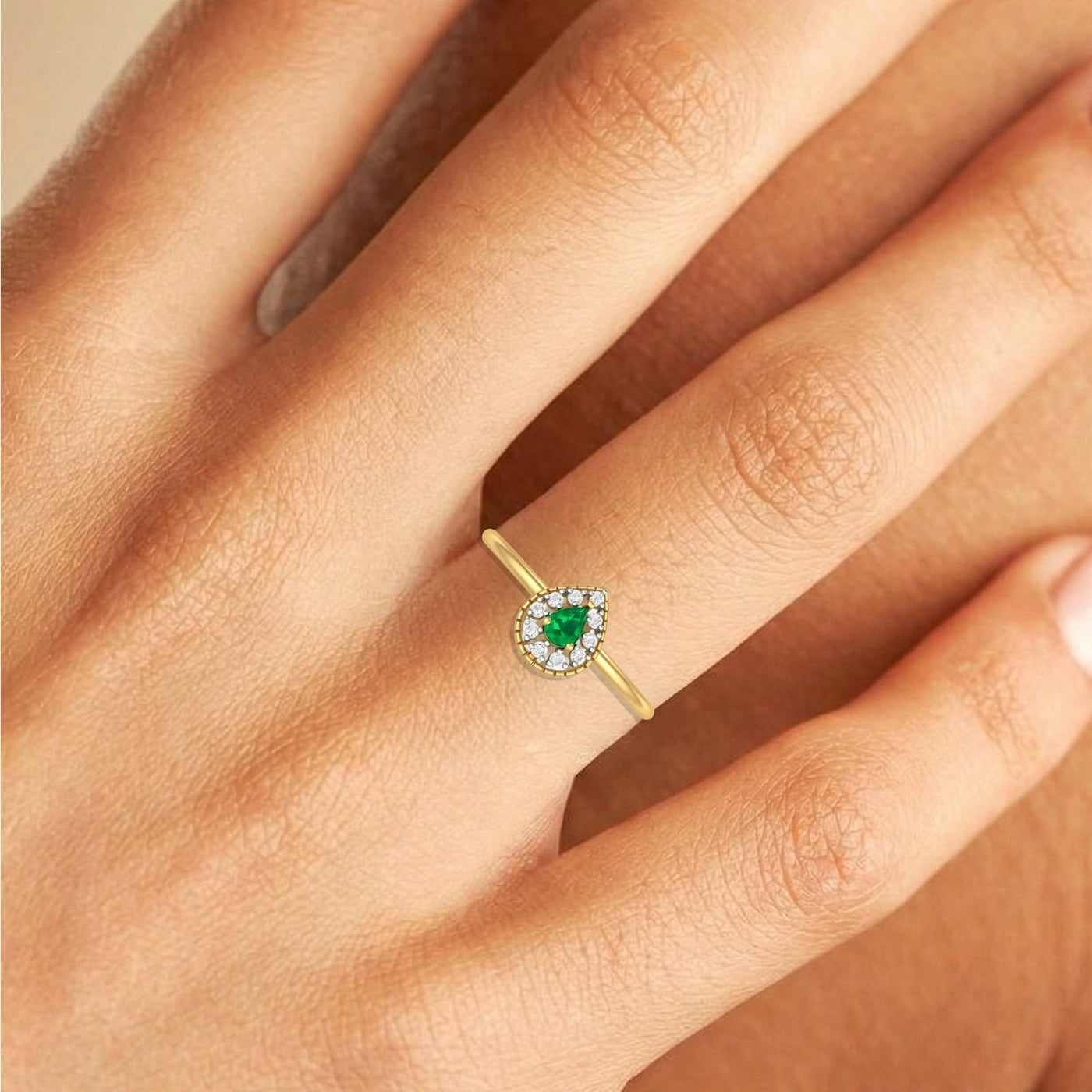Close-up shot of a gold and diamond with teardrop emerald gemsotne setting ring.