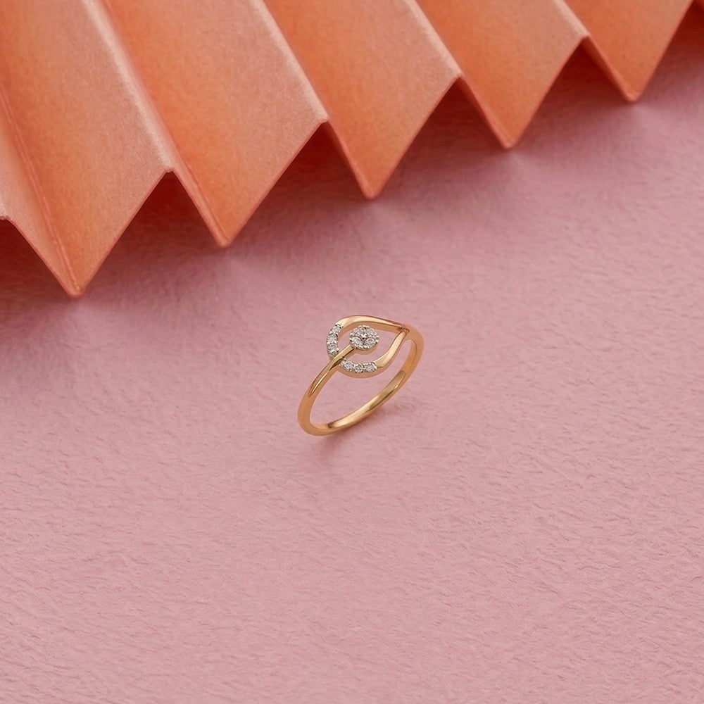 Gold and diamond ring with a cluster setting on a pink textured surface
