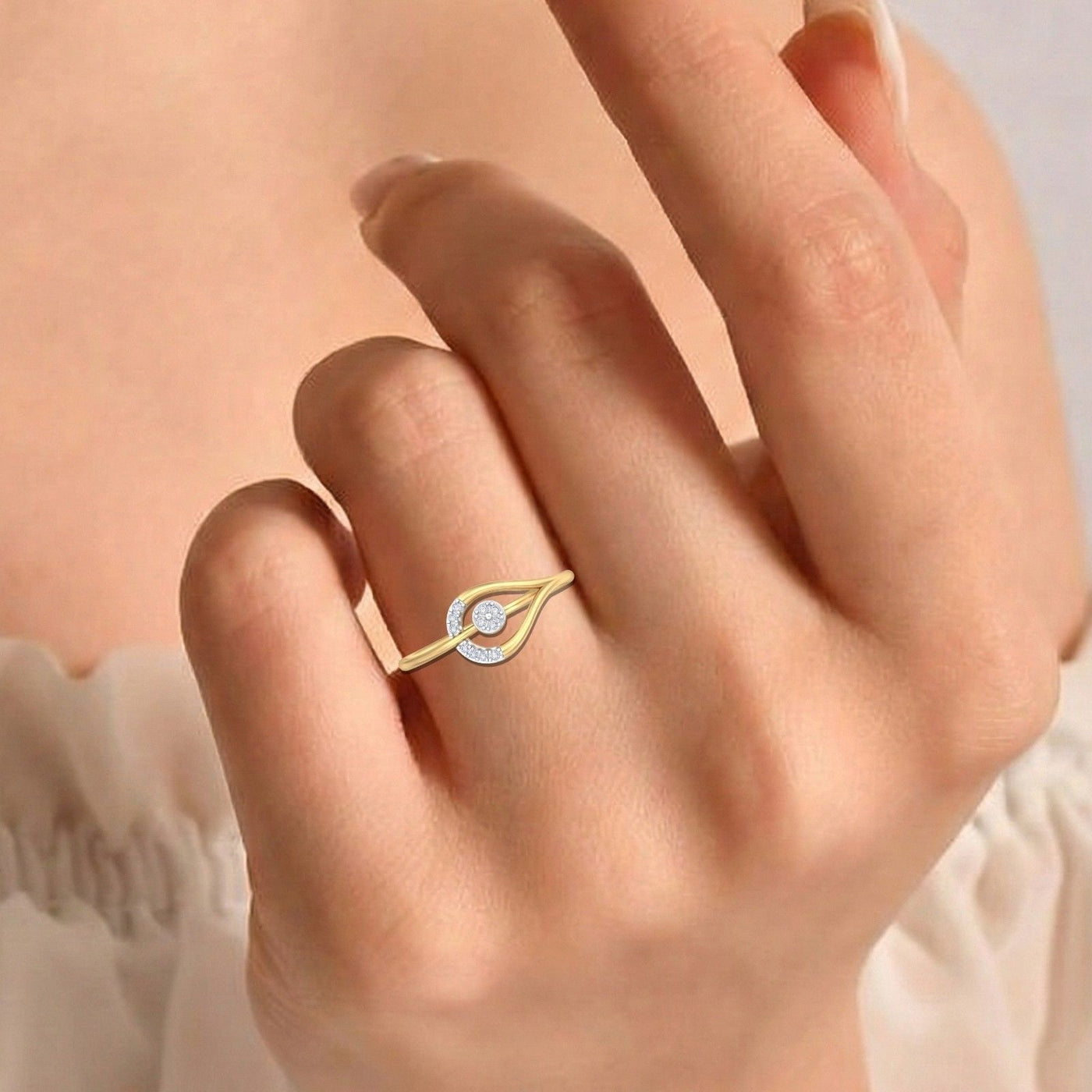 A delicate gold ring with a cluster setting in a teardrop-shaped setting, worn on a person's ring finger.