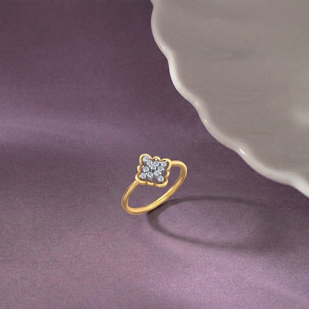 Gold ring with a floral design on a purple fabric background.