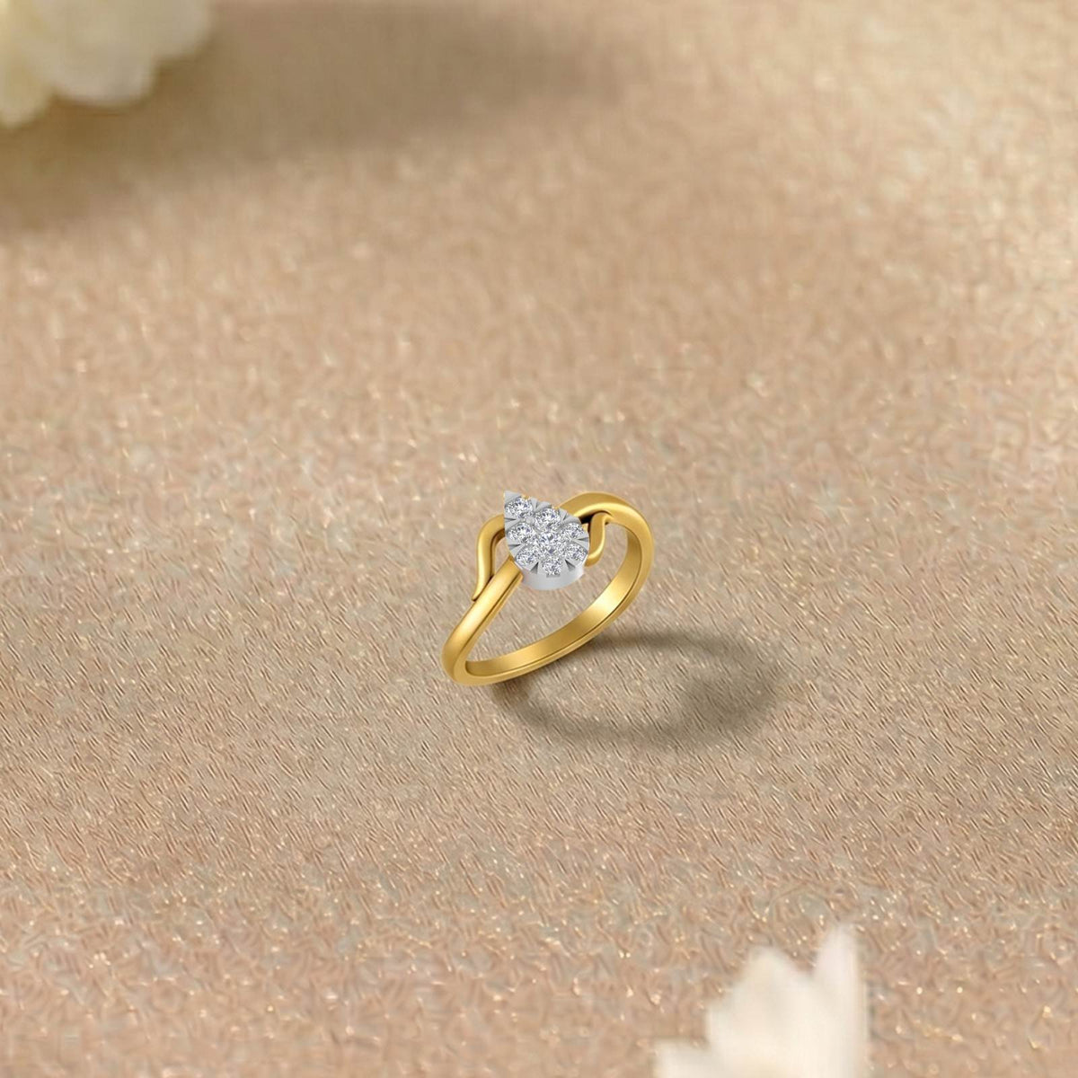 Gold and diamond with cluster teardrop setting ring on a beige surface.