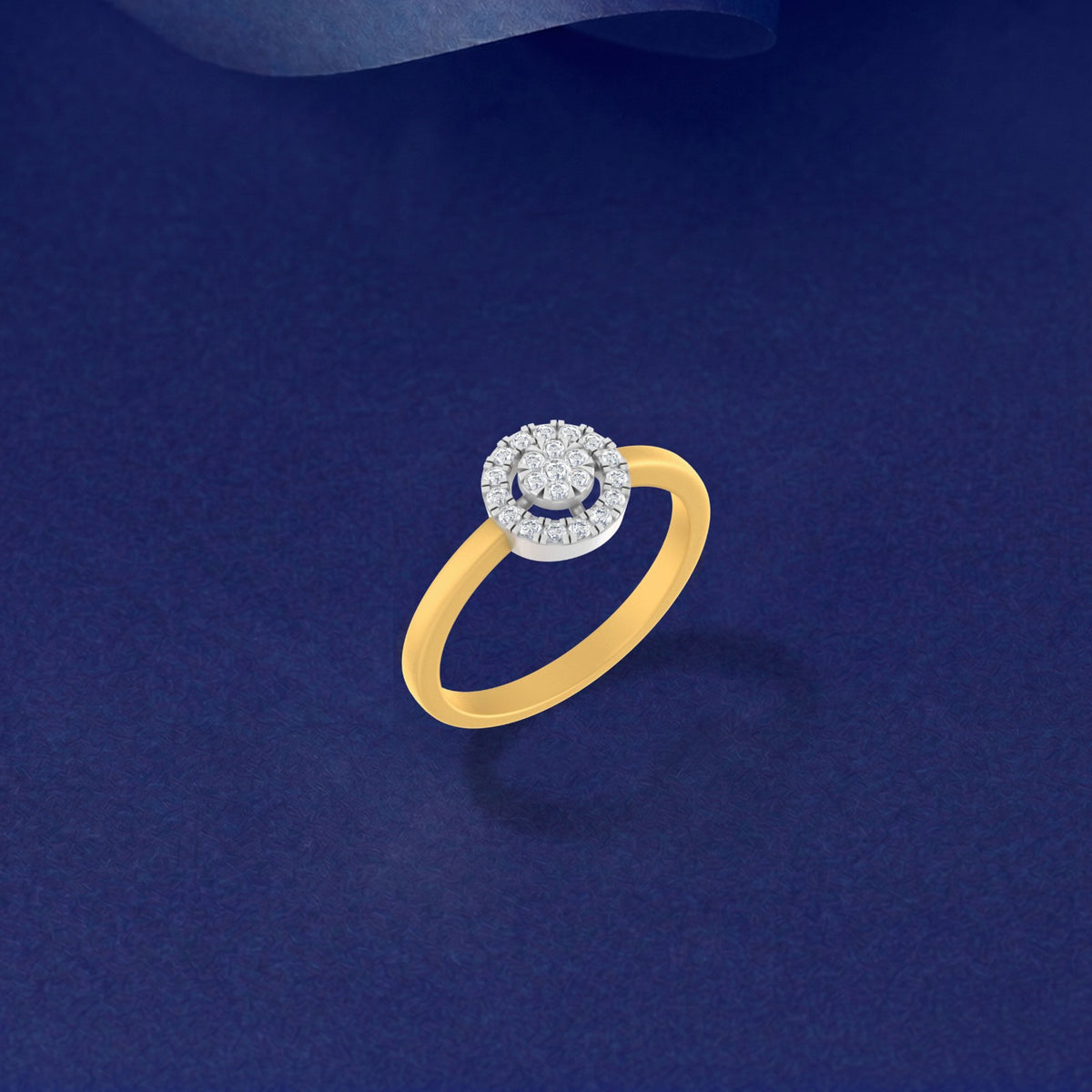 A yellow gold ring with a halo-style setting , on a dark navy blue background.