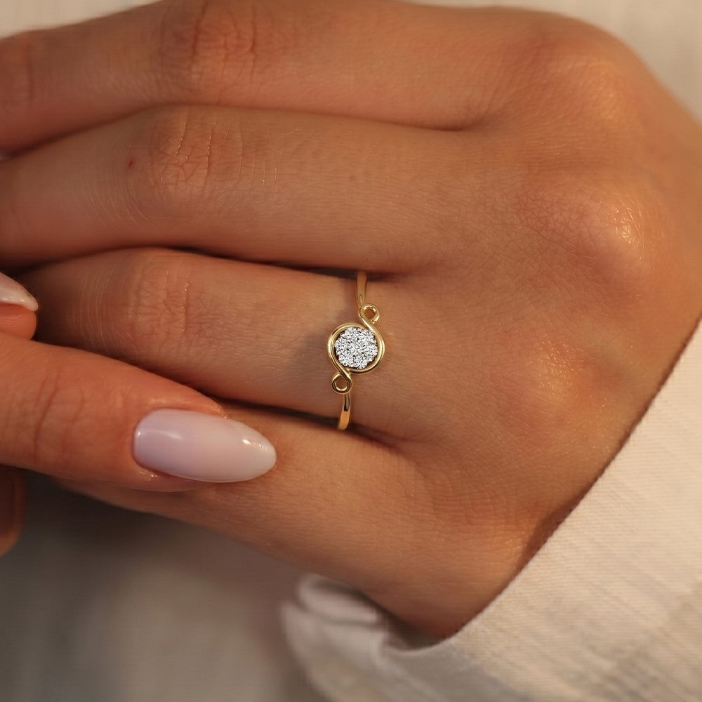 A close-up of a hand wearing a delicate gold and diamond ring.