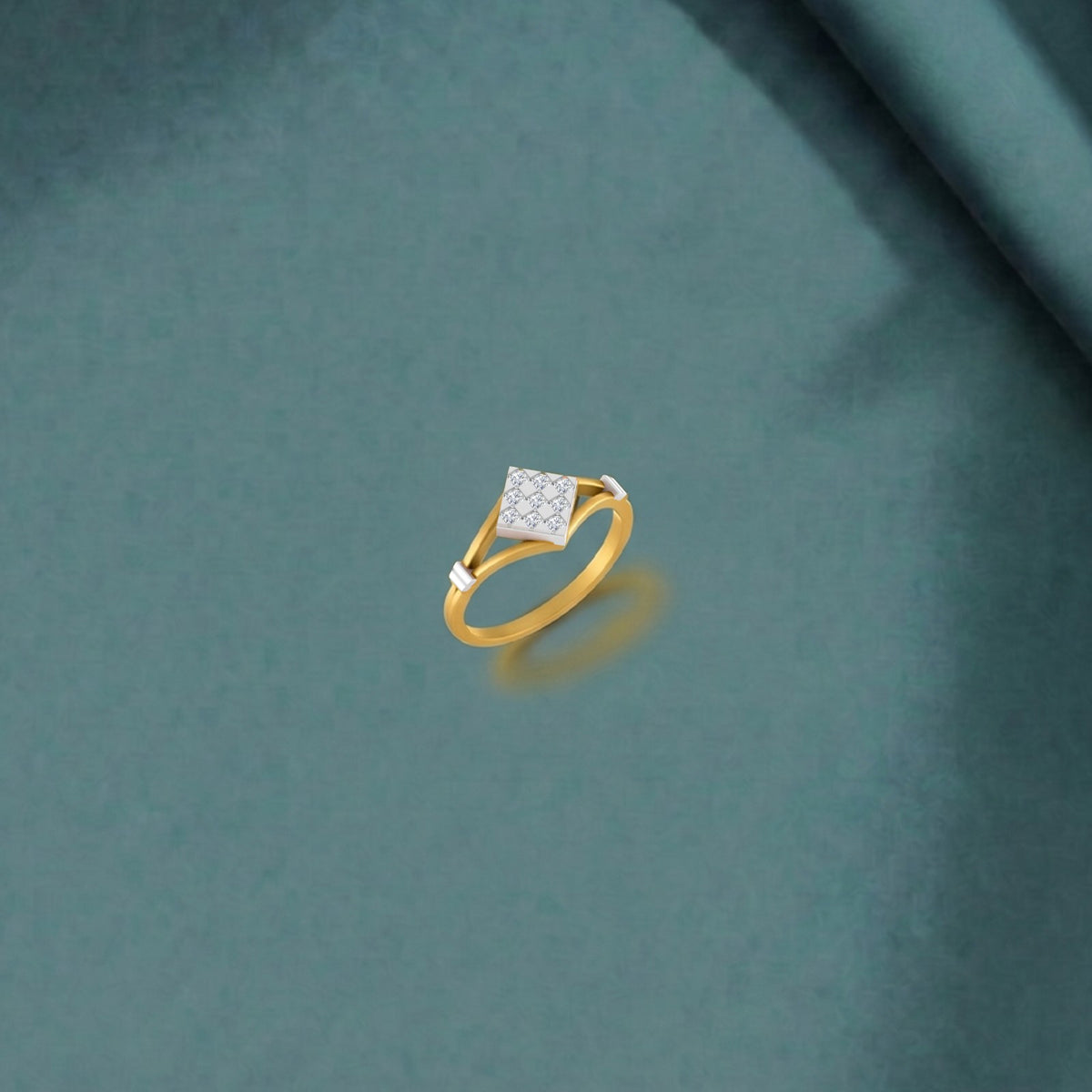 A gold ring with a square pavé diamond center stone, displayed on a textured teal fabric background.