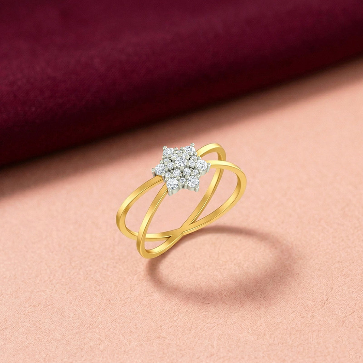 A gold and diamond ring with a floral cluster setting, on a soft peach surface.