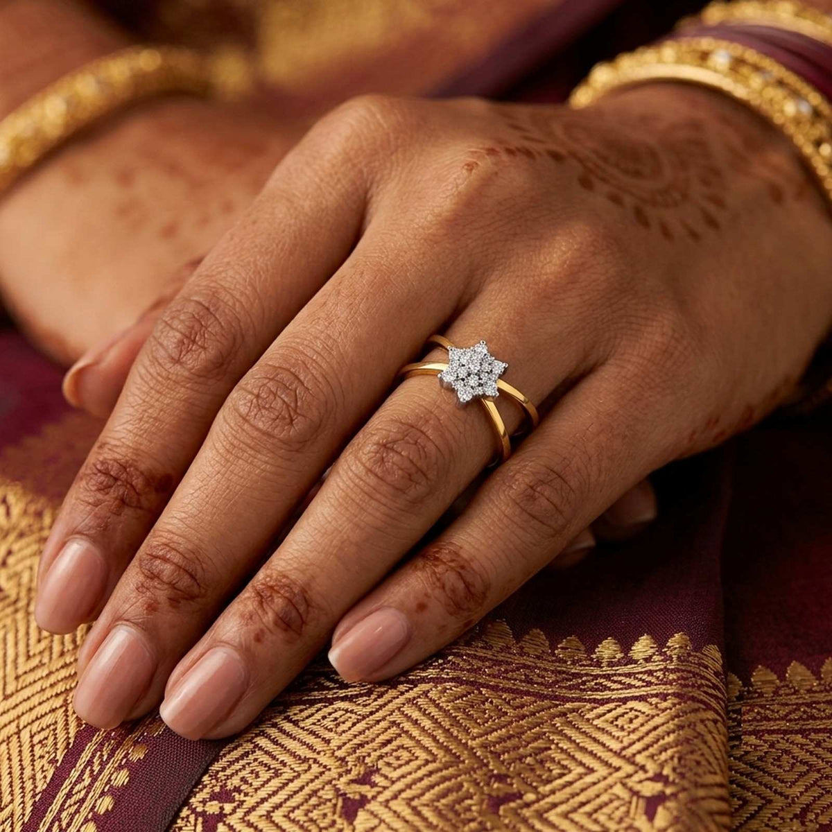 A gold and diamond ring with a floral cluster setting, on a person's finger.