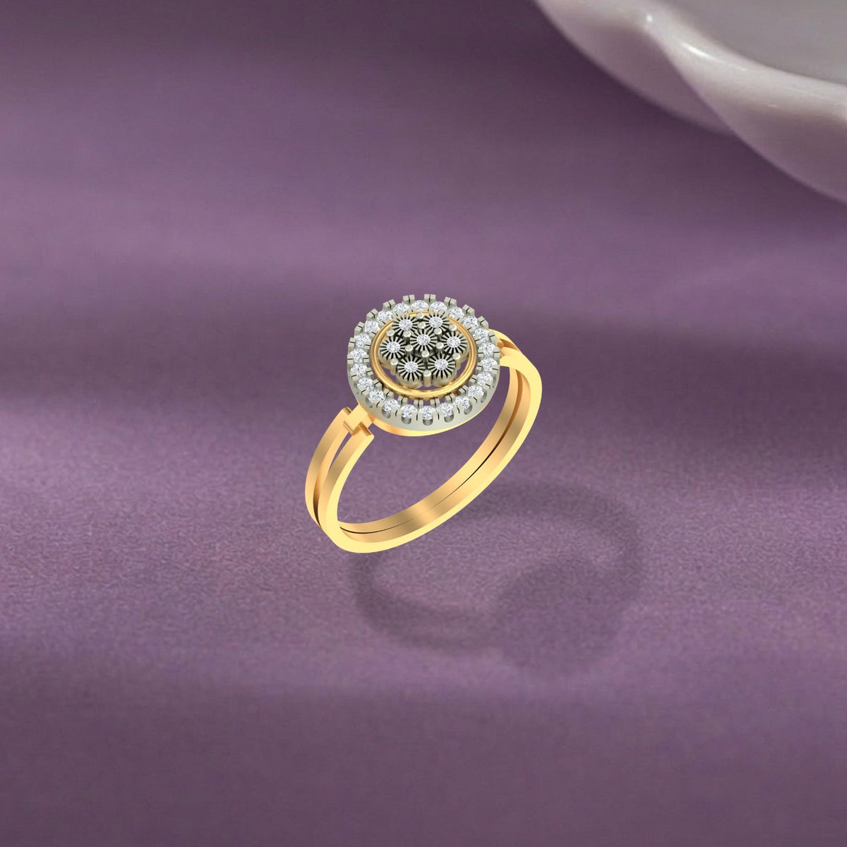 A gold ring with a round diamond halo and a central cluster, displayed on a textured purple surface.