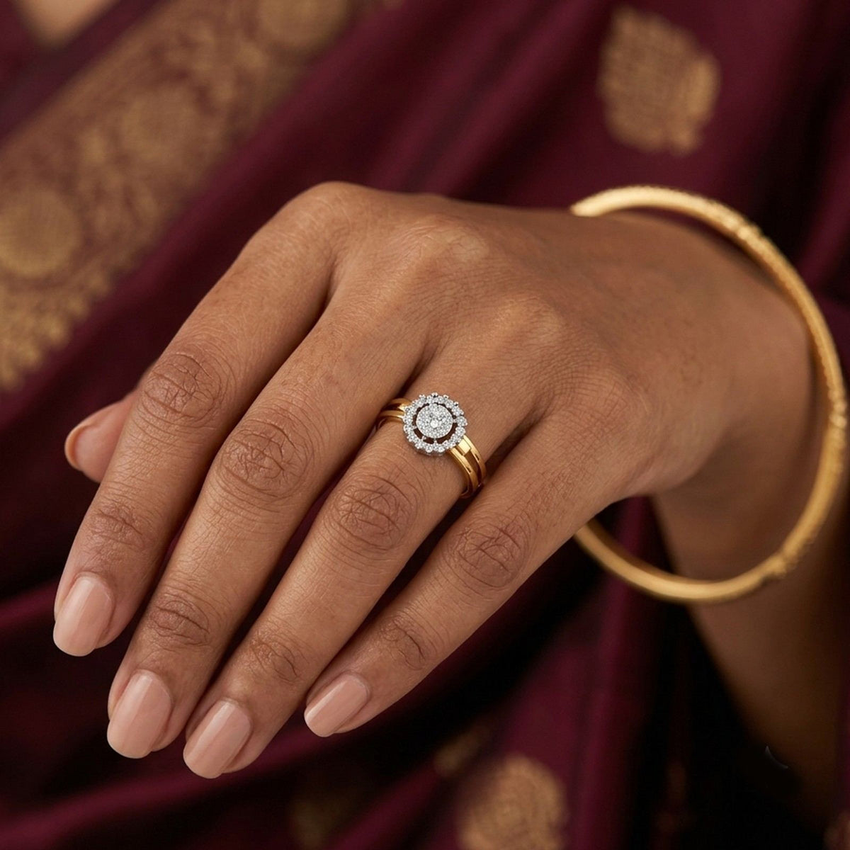 A gold ring with a round halo, displayed on a saree background.