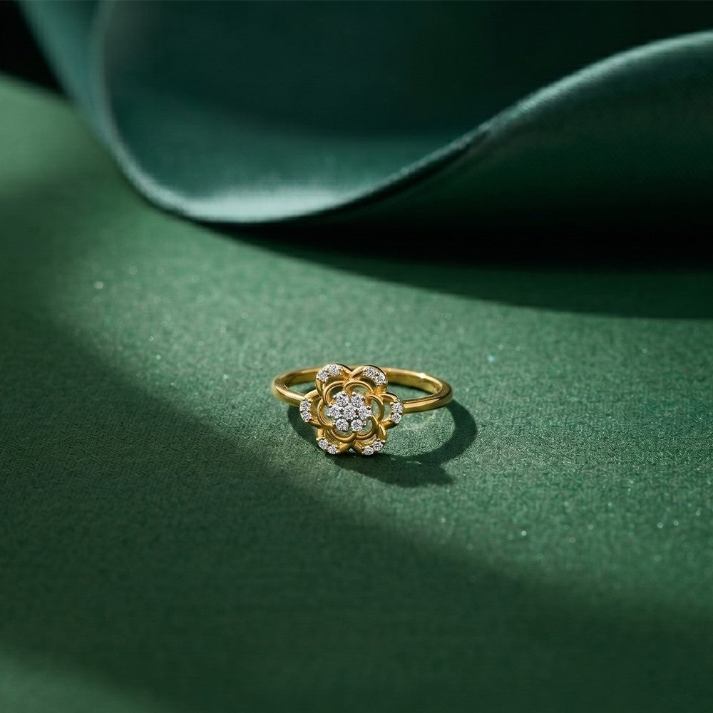 Gold and diamond ring with floral design on a green fabric background
