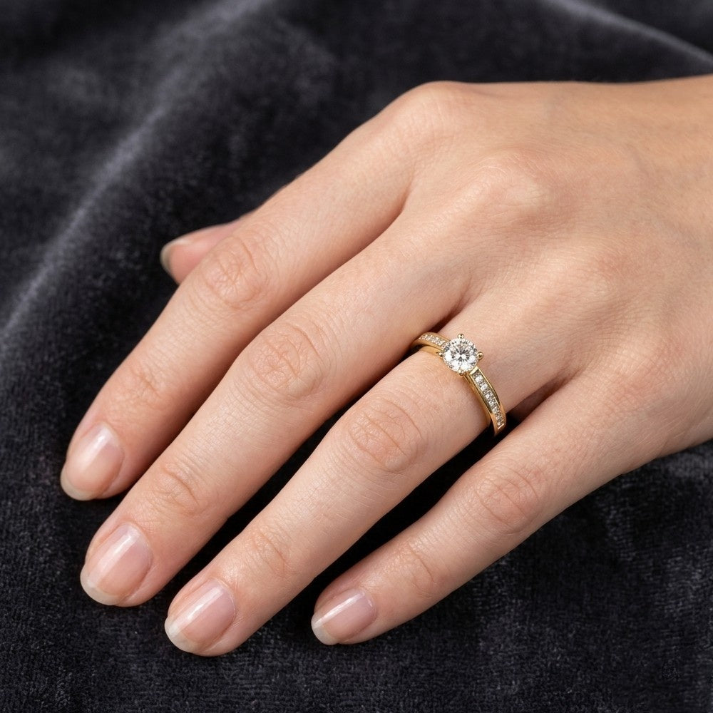 Hand wearing a gold ring with a diamond on a dark fabric background