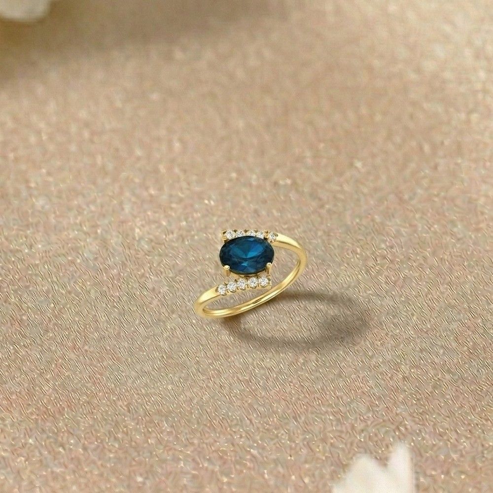 Gold ring with a sapphire gemstone on a beige fabric background