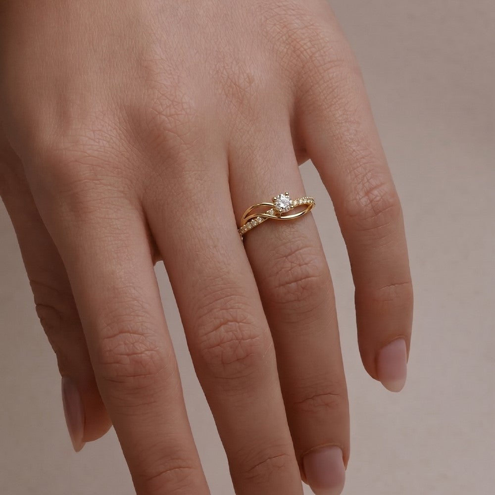 Gold ring with a diamond on a person's finger against a neutral background