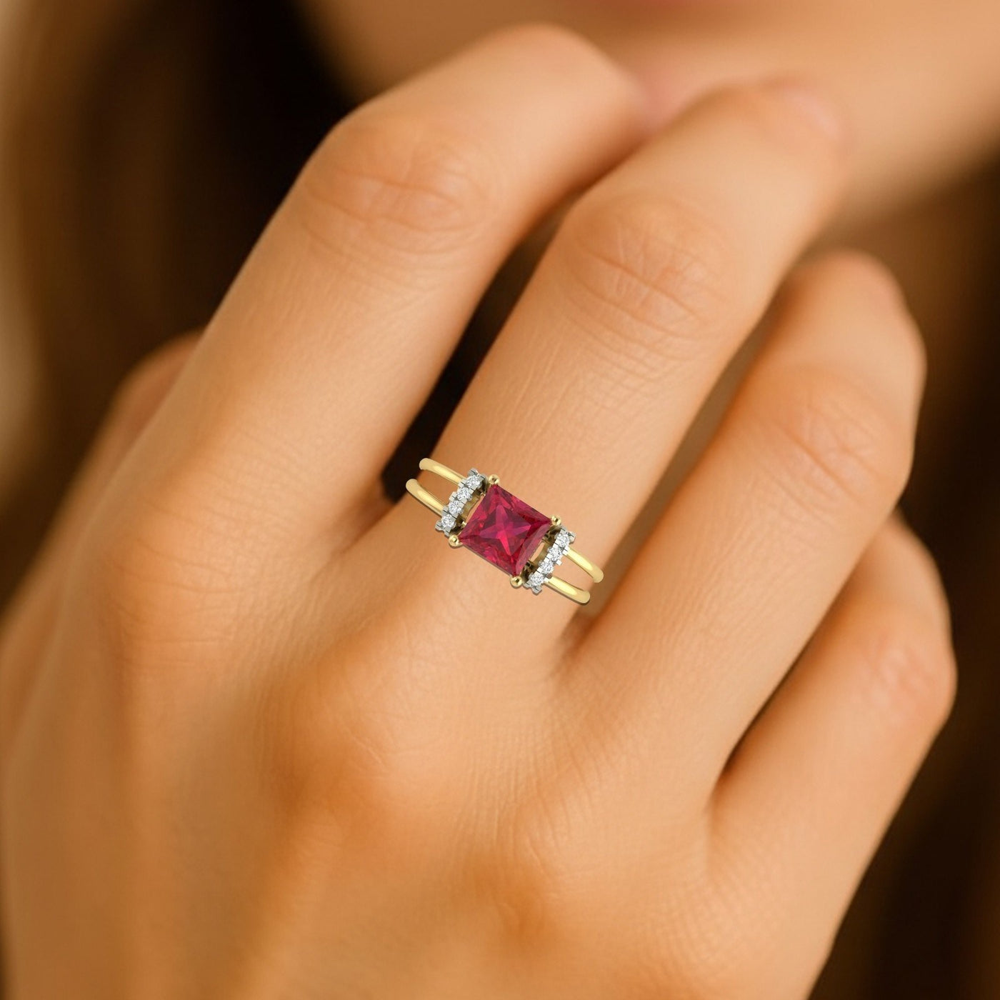 Gold ring with a red gemstone on a hand against a blurred background