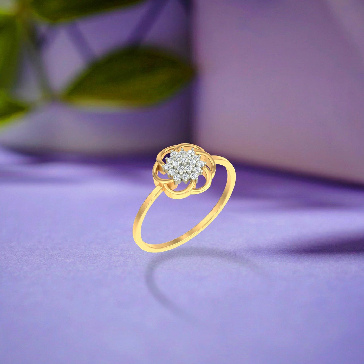 A gold ring with a flower-shaped setting and a cluster on a soft lavender surface with a blurred background.