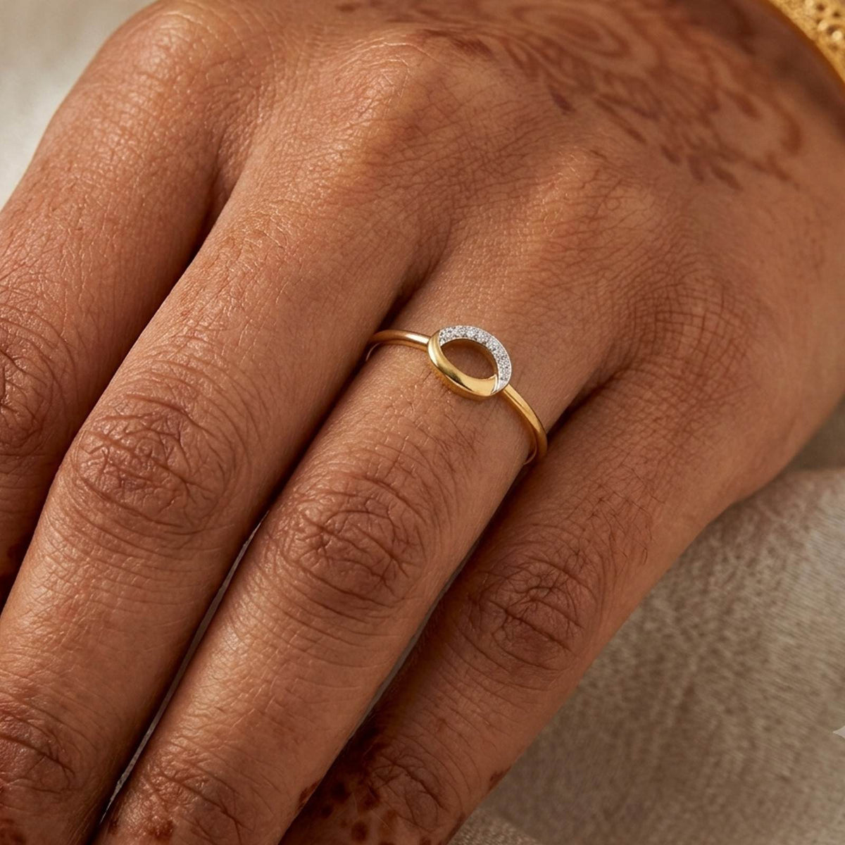 Gold ring with a small diamond on a person's finger.