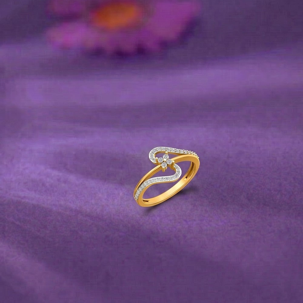 A gold and diamond ring with a cluster design, resting on a purple textured fabric background.