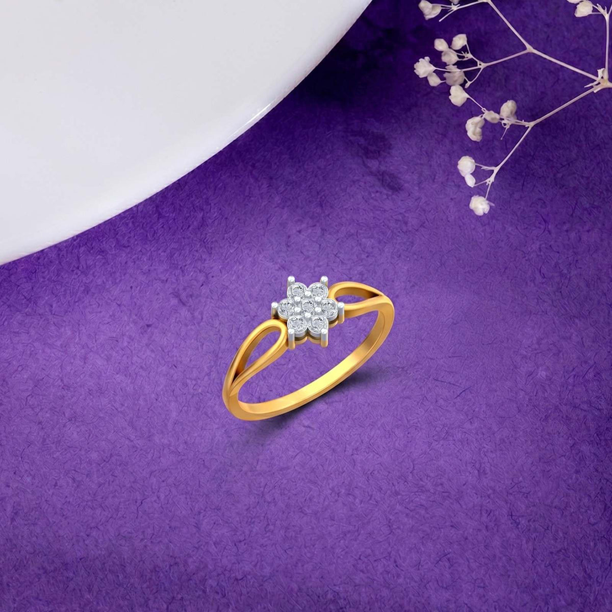 A gold ring with a diamond cluster setting, displayed on a textured purple surface.