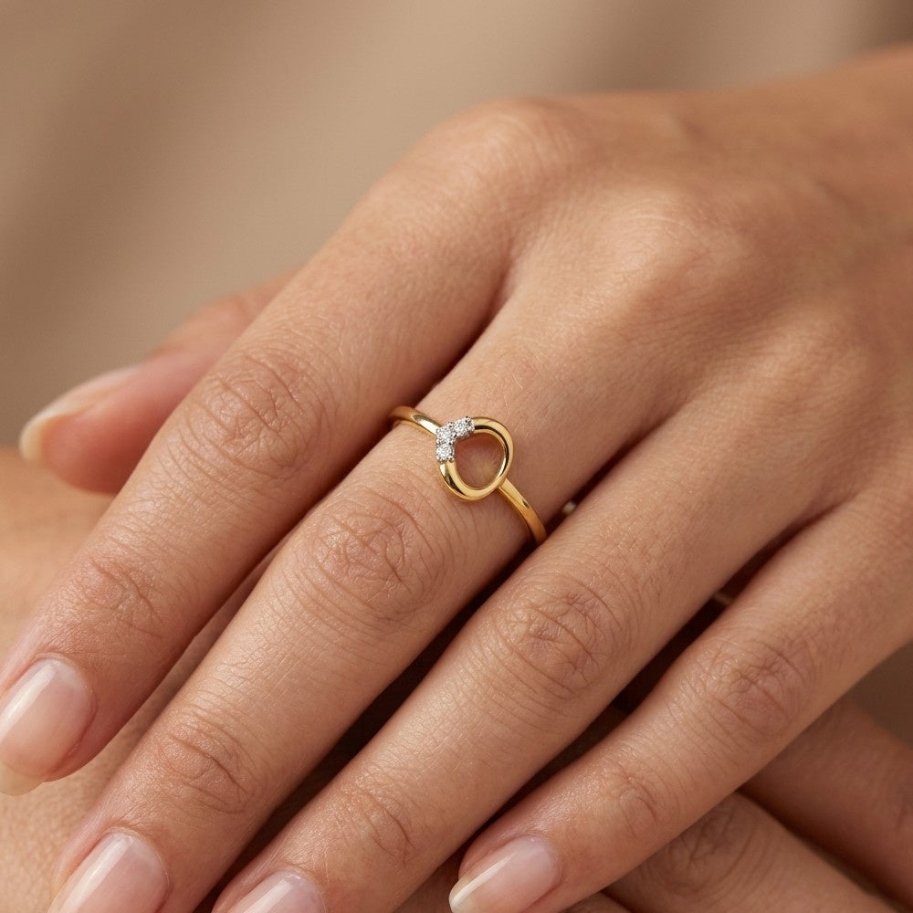 A close-up, top-down view of a hand wearing a delicate yellow gold ring