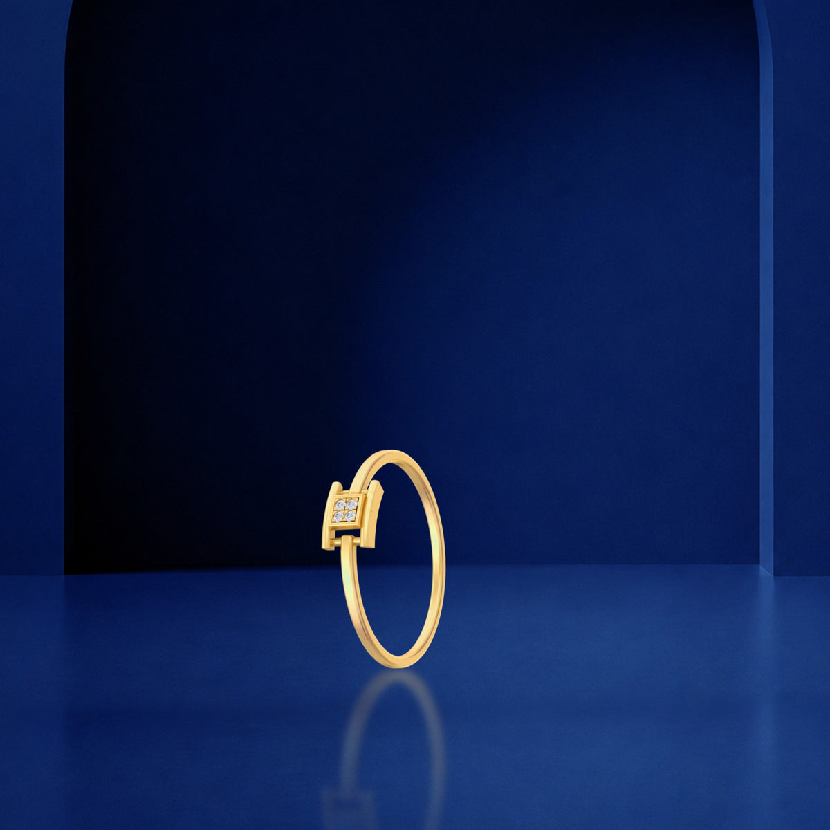 A gold ring with a square-cut diamond center, standing upright on a reflective dark blue surface against a matching blue background.