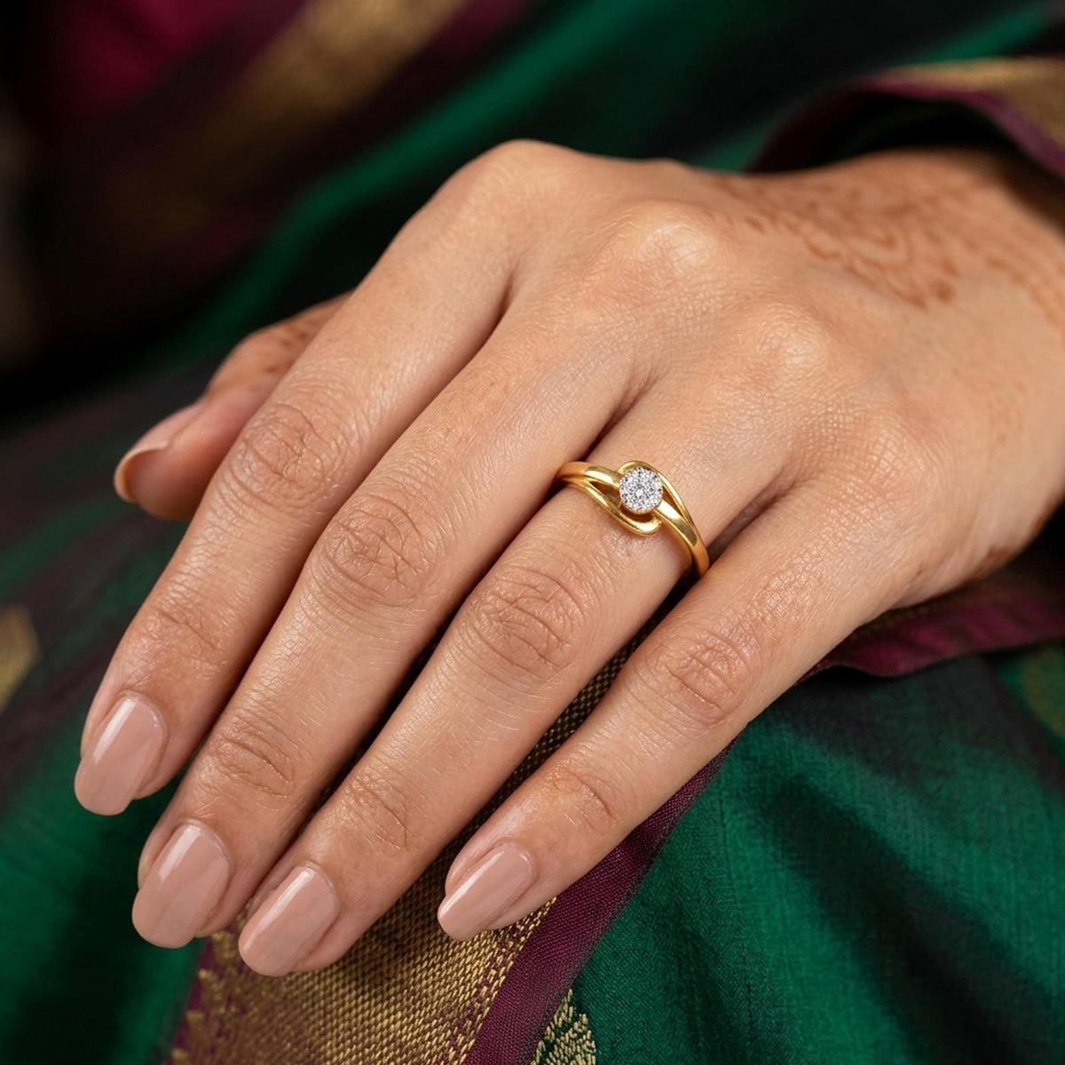 Gold ring with a cluster diamond setting  hand against a green background