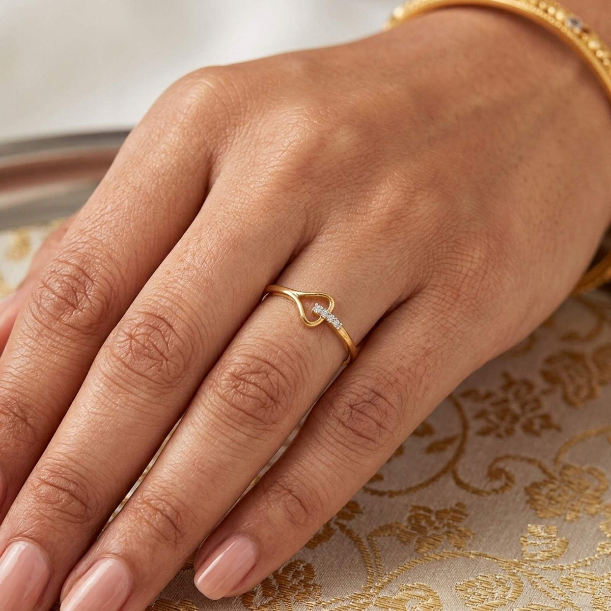 Gold and diamond women's ring on a hand against a background