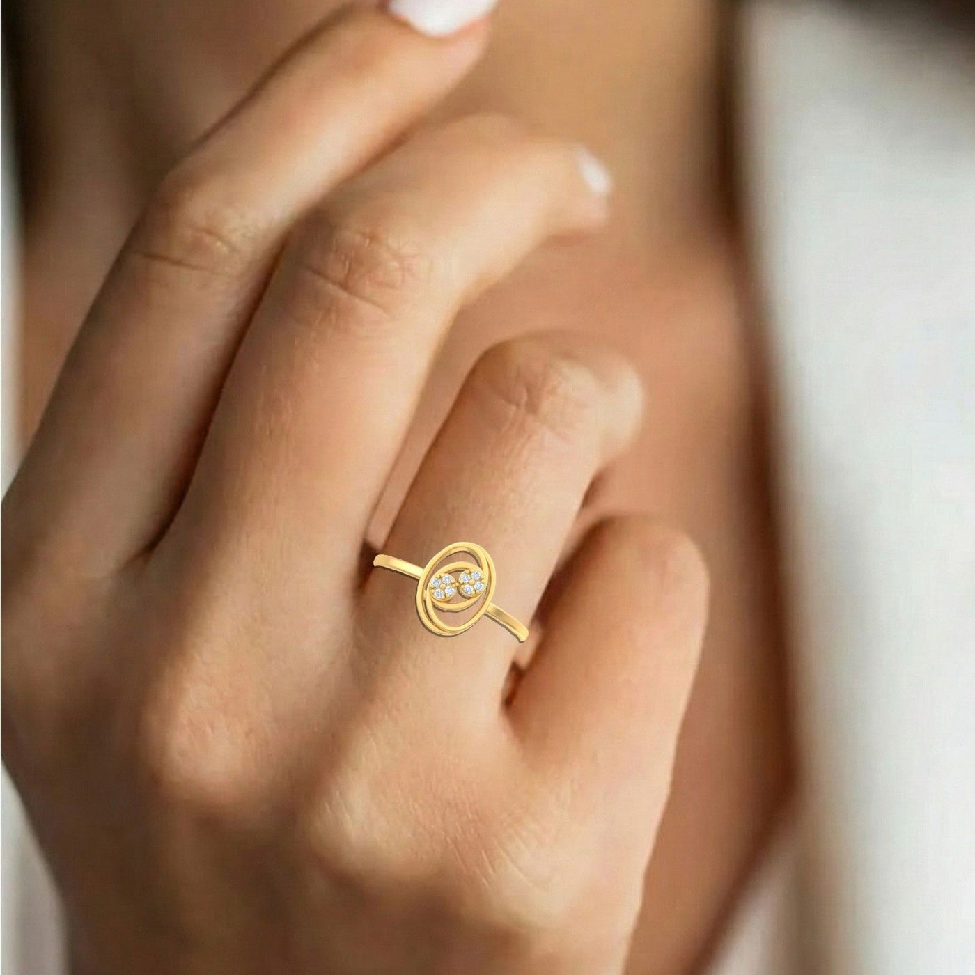 Gold and diamonds ring on a person's finger against a neutral background