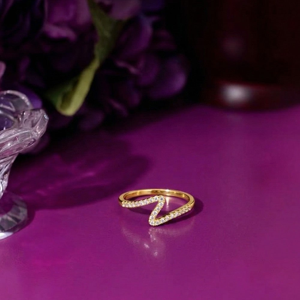 Gold and diamond half-eternity ring on a purple reflective surface.
