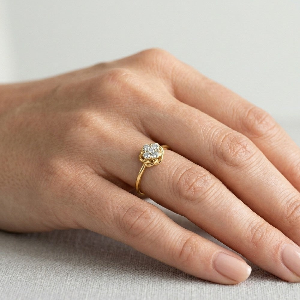 Gold ring with a diamond on a person's finger against a neutral background

