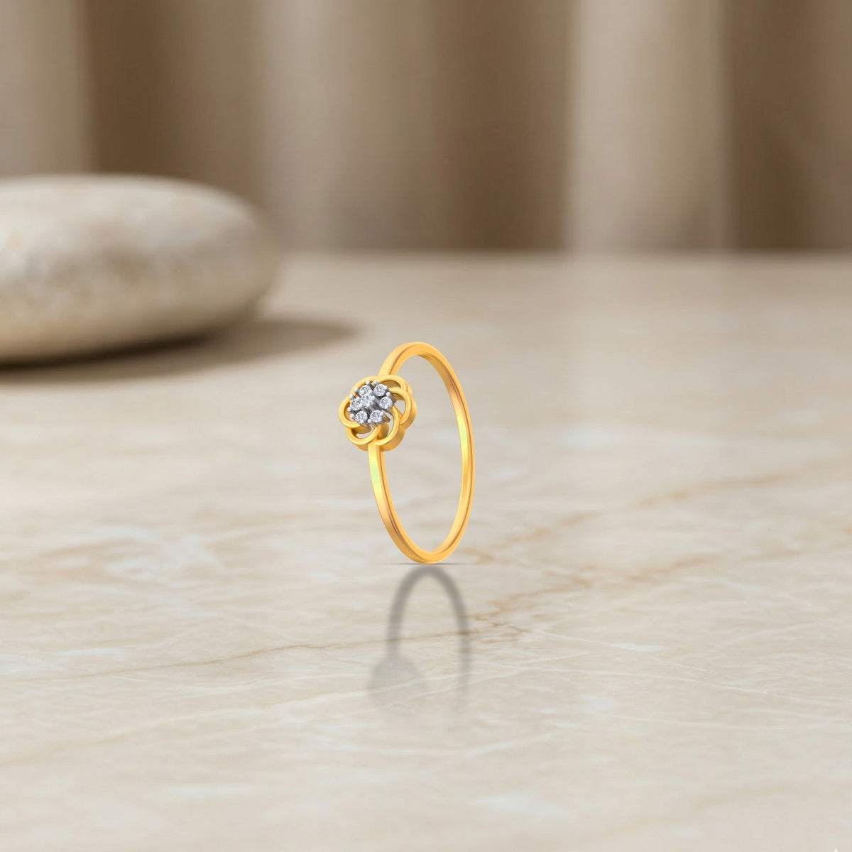 Gold and diamond with floral-design cluster setting on a beige surface.